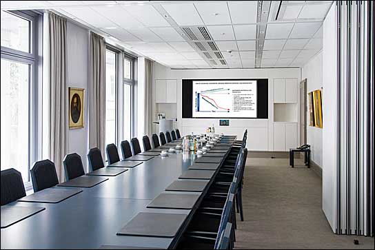 Der teilbare Hauptkonferenzraum mit Blick auf die Medienwand "Modern" mit 90-Zoll-Monitor und integriertem Videokonferenzsystem.